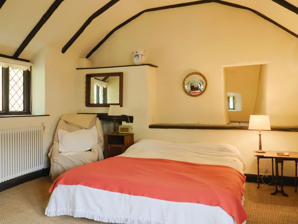 A bedroom with a bed and armchair at Hole House in Branscombe