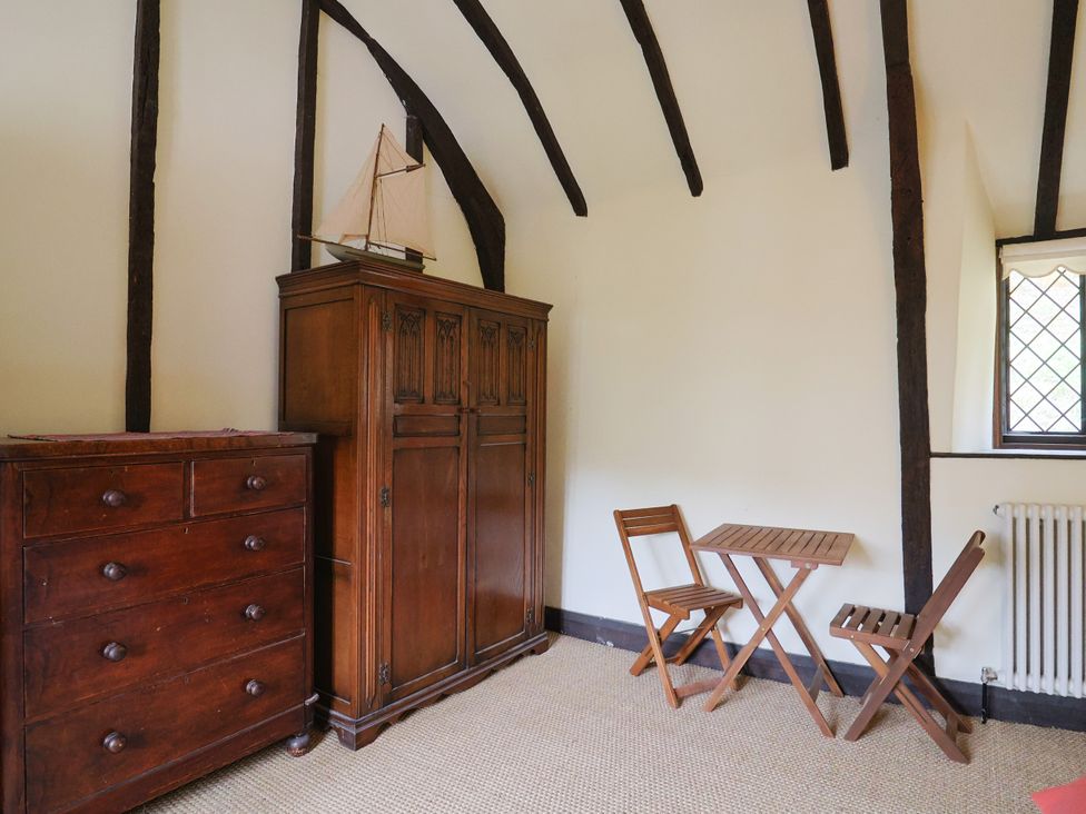 A bedroom with a wardrobe, chest of drawers, table, and chairs at Hole House in Branscombe