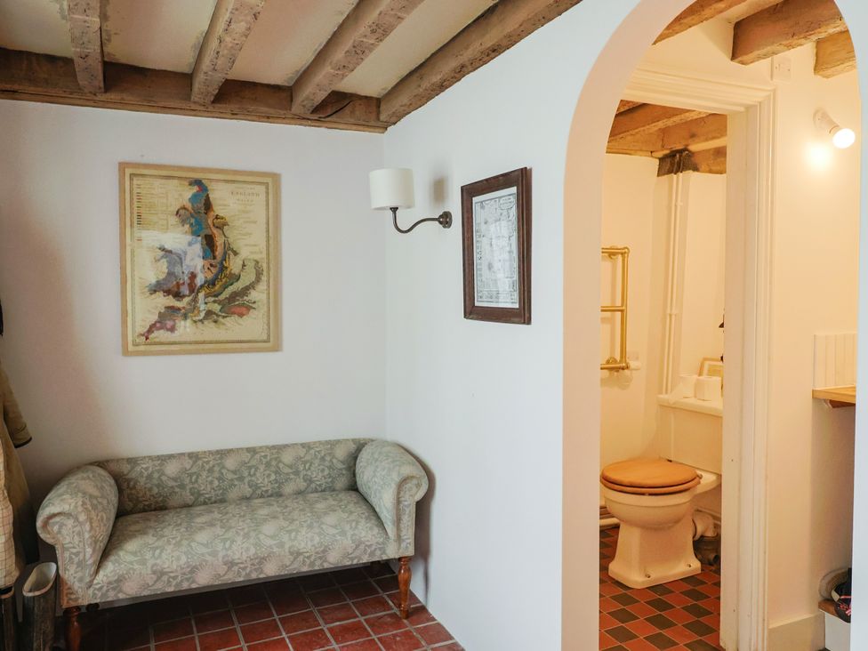 A bathroom with a toilet and sink visible from an adjacent room at Hole House in Branscombe