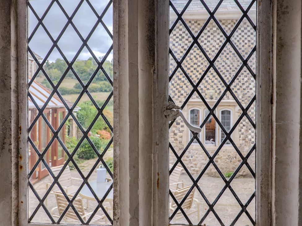 A view through a window showing an outdoor seating area at Hole House in Branscombe
