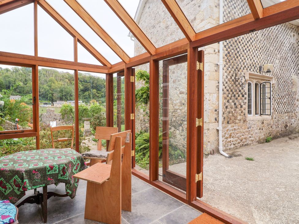 A conservatory with a table and chairs at Hole House in Branscombe