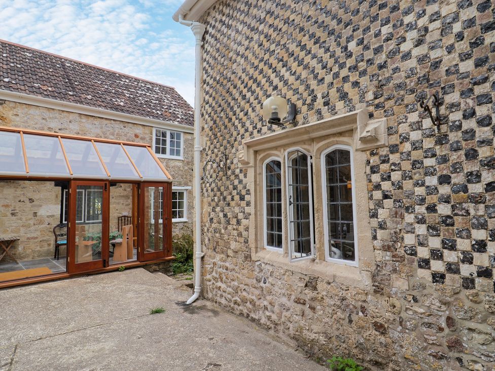 An outdoor view of a stone wall and conservatory at Hole House in Branscombe