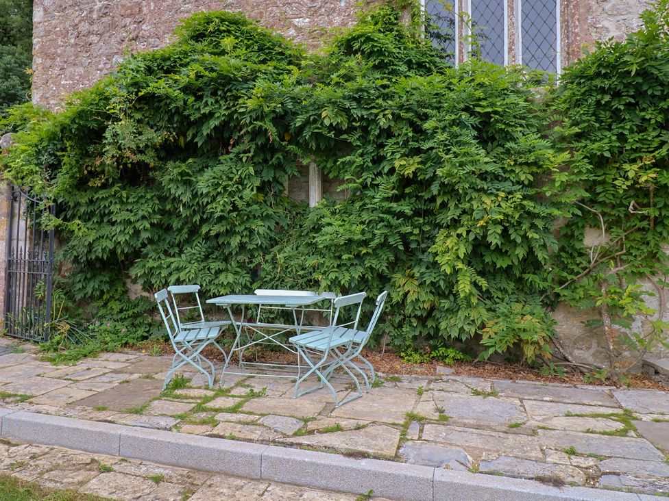 A table and chairs near a wall covered with vines at Hole House in Branscombe
