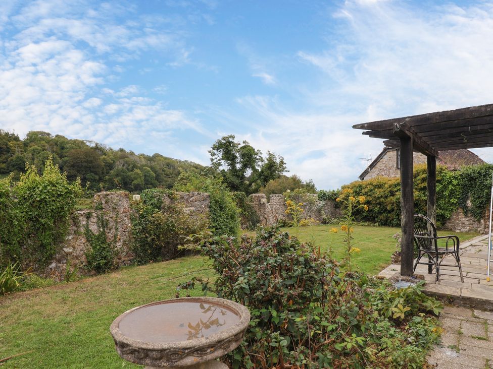 A garden with a bird bath and stone wall at Hole House in Branscombe