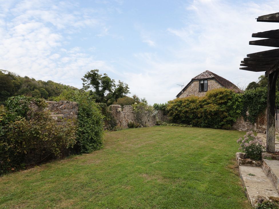 A garden with grass and a stone wall at Hole House in Branscombe