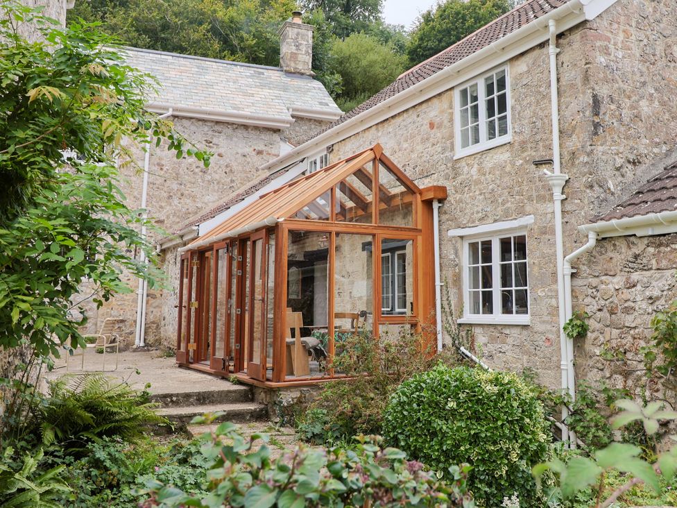 A conservatory attached to a stone house at Hole House in Branscombe