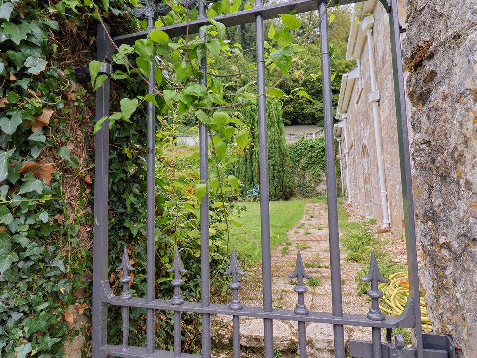 A garden with a gate and stone wall at Hole House in Branscombe