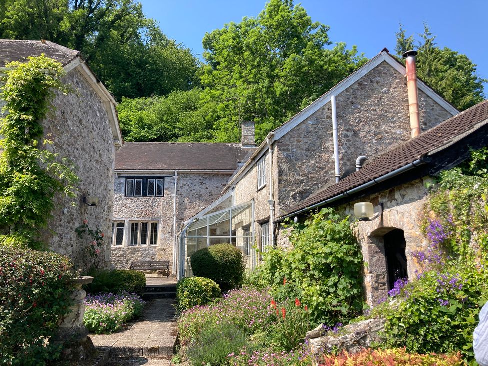 An outdoor area with stone houses and a glass conservatory at Hole House in Branscombe