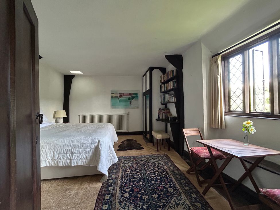 A bedroom with a bed and a small dining area at Hole House in Branscombe