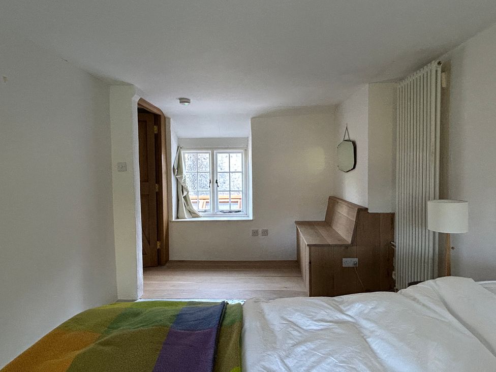 A bedroom with a bed, a window, and a bench at Hole House Branscombe