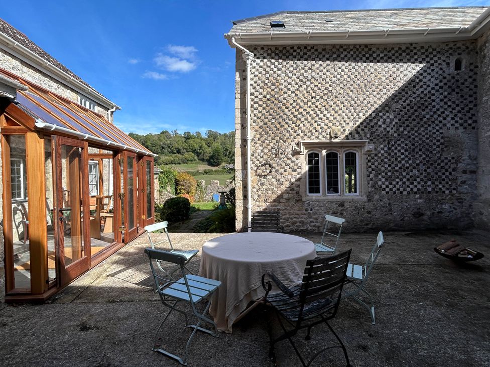 An outdoor patio with a table and chairs at Hole House in Branscombe