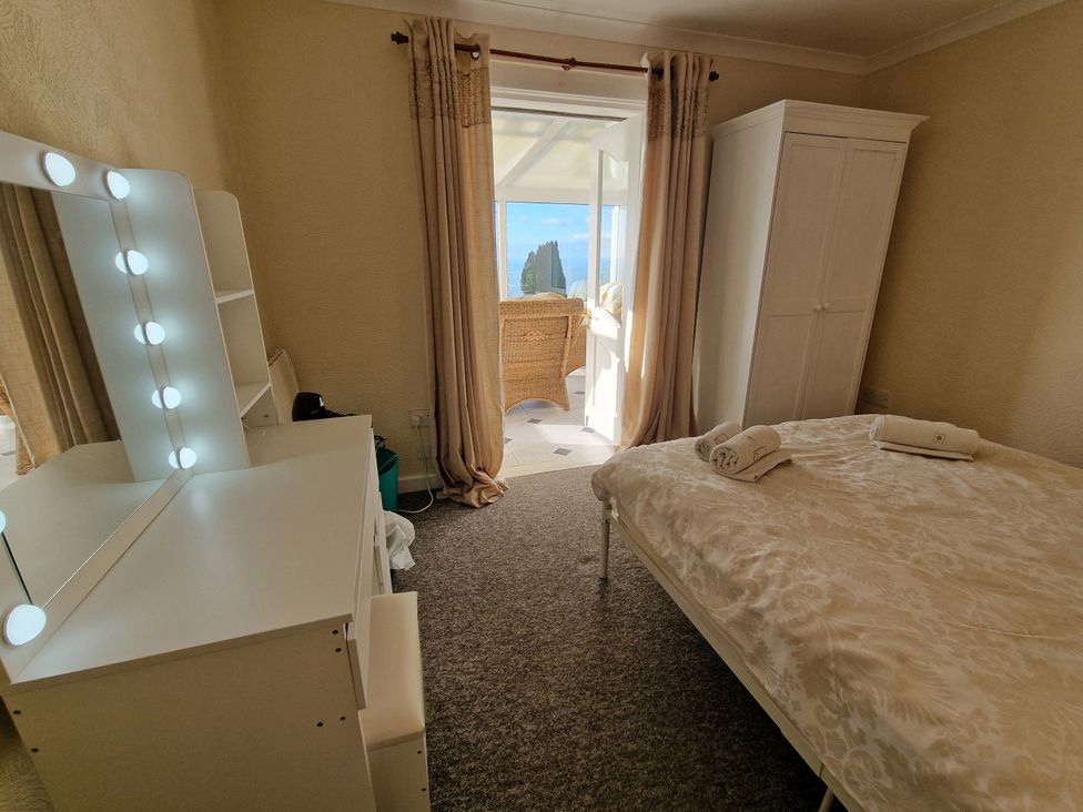 A bedroom with a bed and a dressing table at Woodland Roost in Barmouth