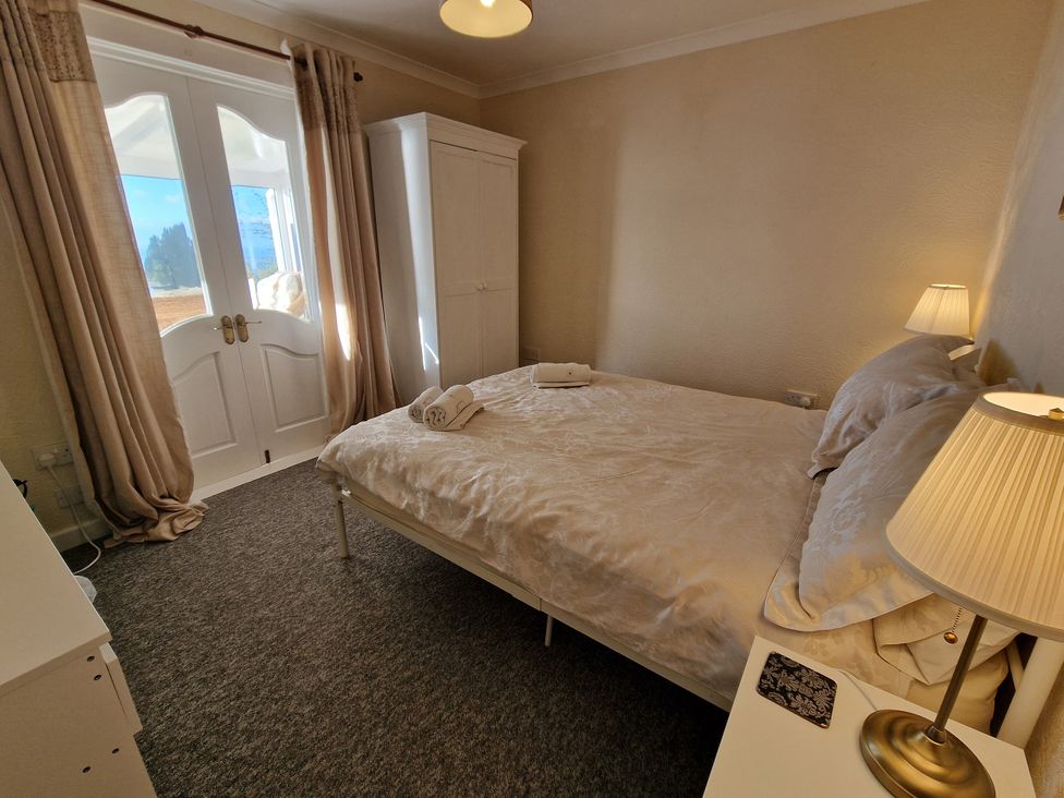 A bedroom with a bed and wardrobe at Woodland Roost in Barmouth