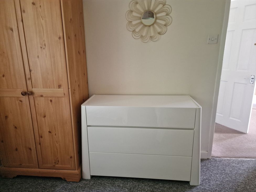 A bedroom with a wardrobe and a chest of drawers at Woodland Roost in Barmouth