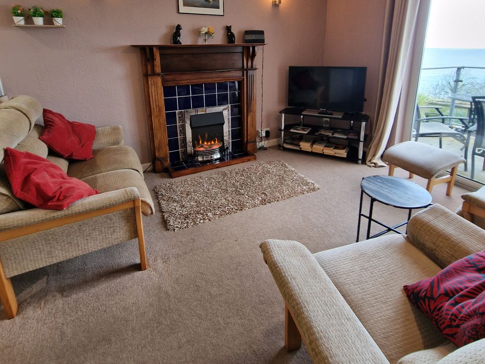 A living room with a fireplace and television at Woodland Roost in Barmouth