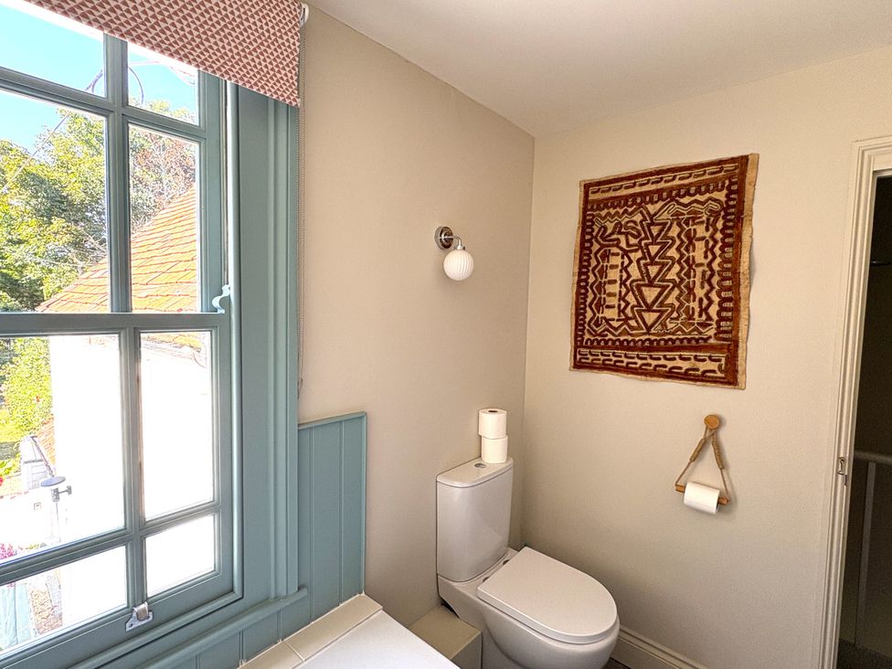 A bathroom with a toilet and wall art at 8 Mariners Terrace Chichester