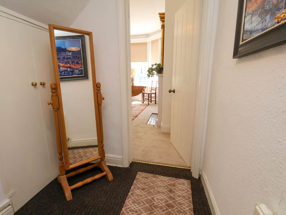 A hallway with a full-length wooden mirror and a patterned rug looking into a room with chairs and a table at Flat 1 in Scarborough