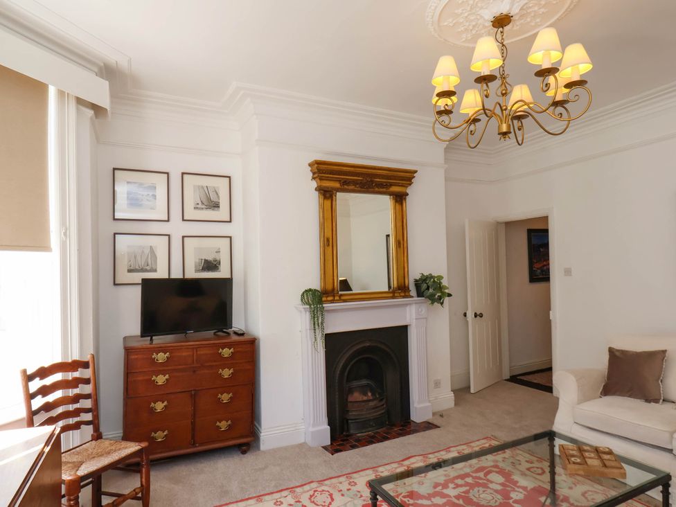 A living room with a fireplace mirror television chest of drawers chair and sofa at Flat 1 in Scarborough