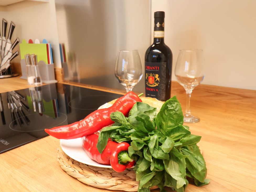 A kitchen counter with a bottle of Chianti wine two wine glasses red peppers and fresh green leafy vegetables at Flat 1 in Scarborough