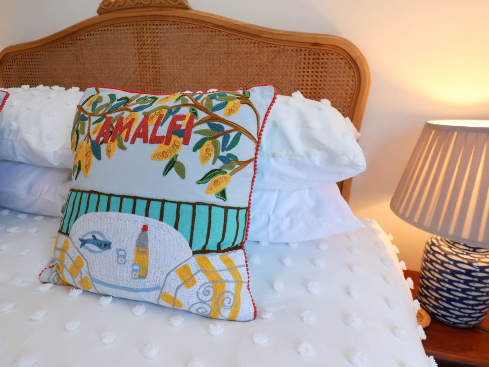 A bed with a decorative Amalfi pillow white bedding and a table lamp at Flat 1 in Scarborough
