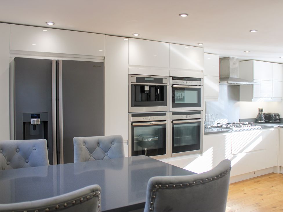 A kitchen with a refrigerator, ovens, and a gas stove at Old Police House in Salcombe