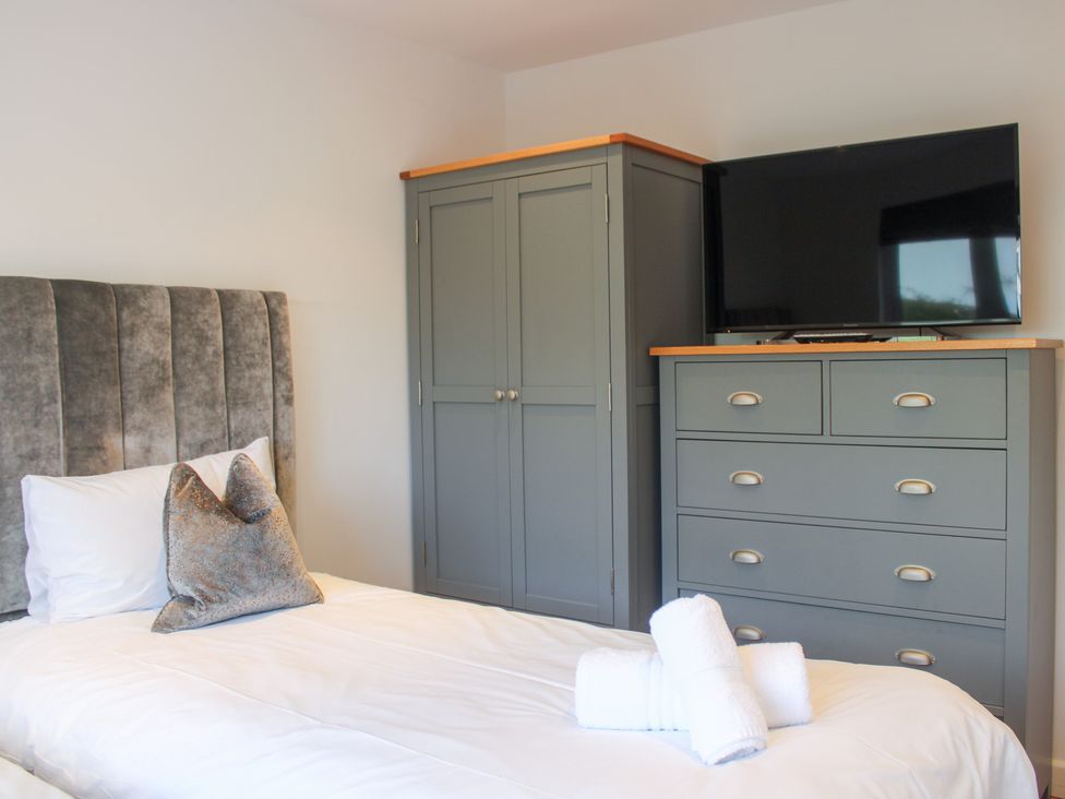 A bedroom with a bed, wardrobe, and television at the Old Police House in Salcombe