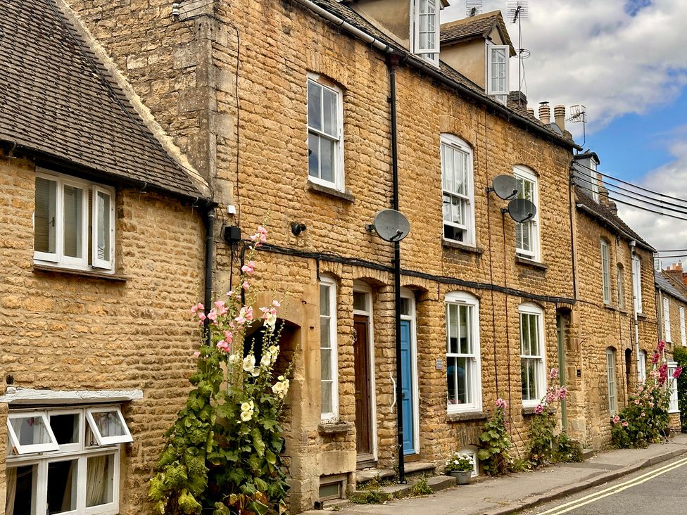 A row of stone buildings with windows and doors at Lamorna Cottage in Chipping Norton