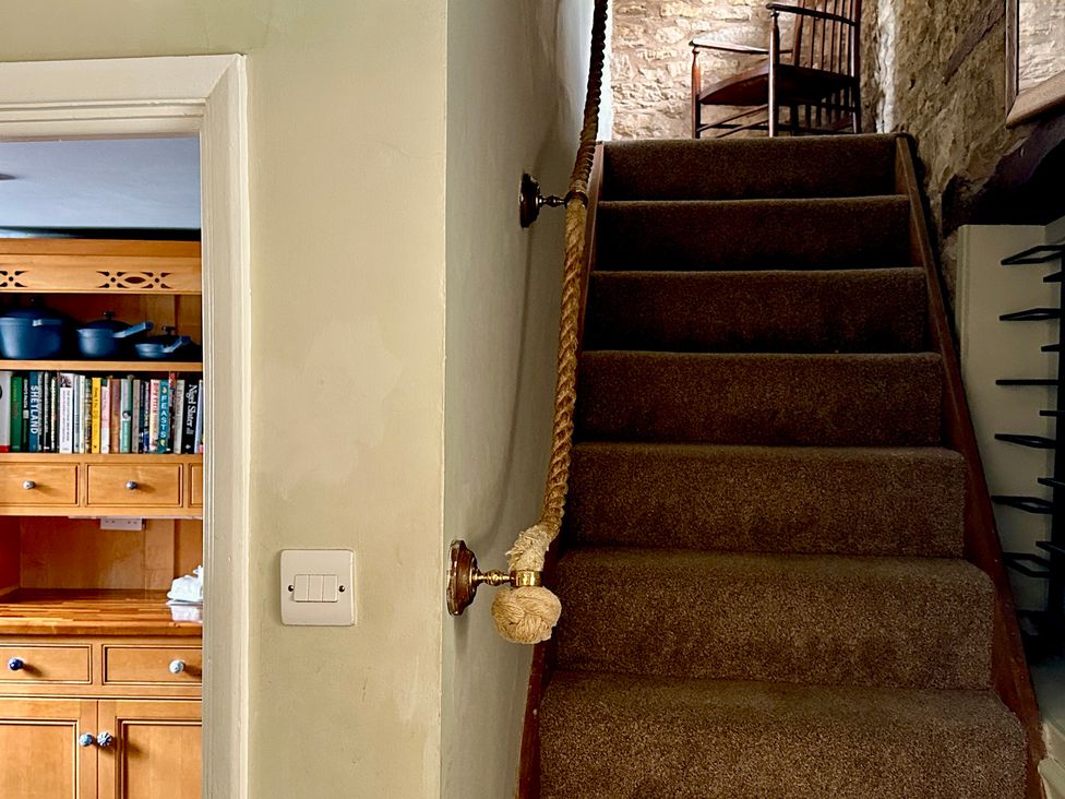 A staircase with an open doorway leading to a kitchen at Lamorna Cottage in Chipping Norton