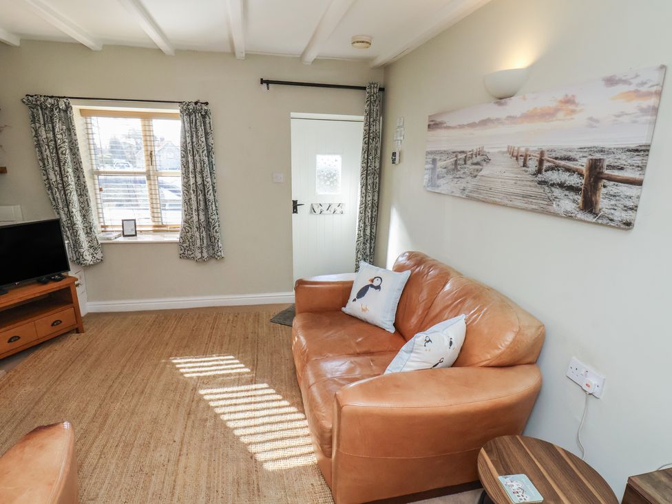 A living room with a sofa and television at Puffin's Nest in 