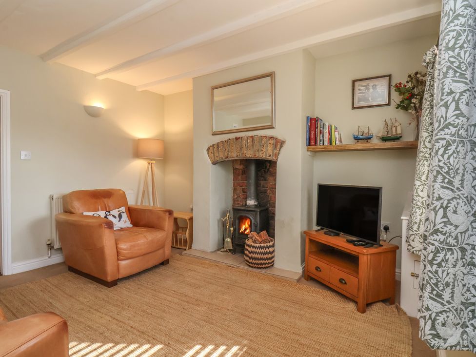 A living room with an armchair and fireplace at Puffin's Nest