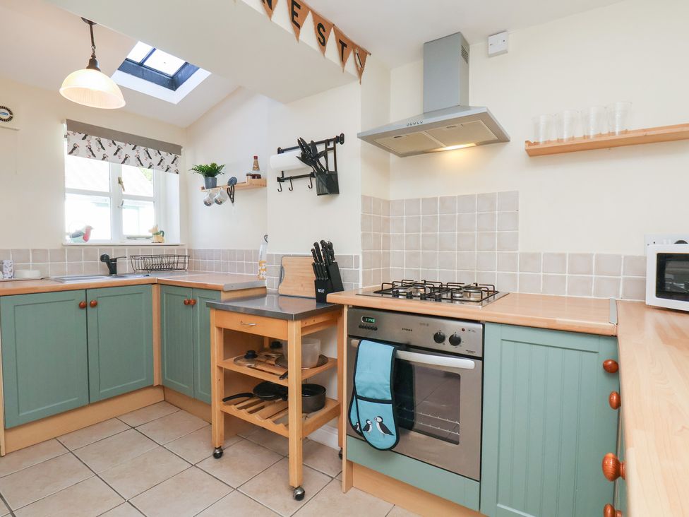 A kitchen with cabinets sink and stove at Puffin's Nest