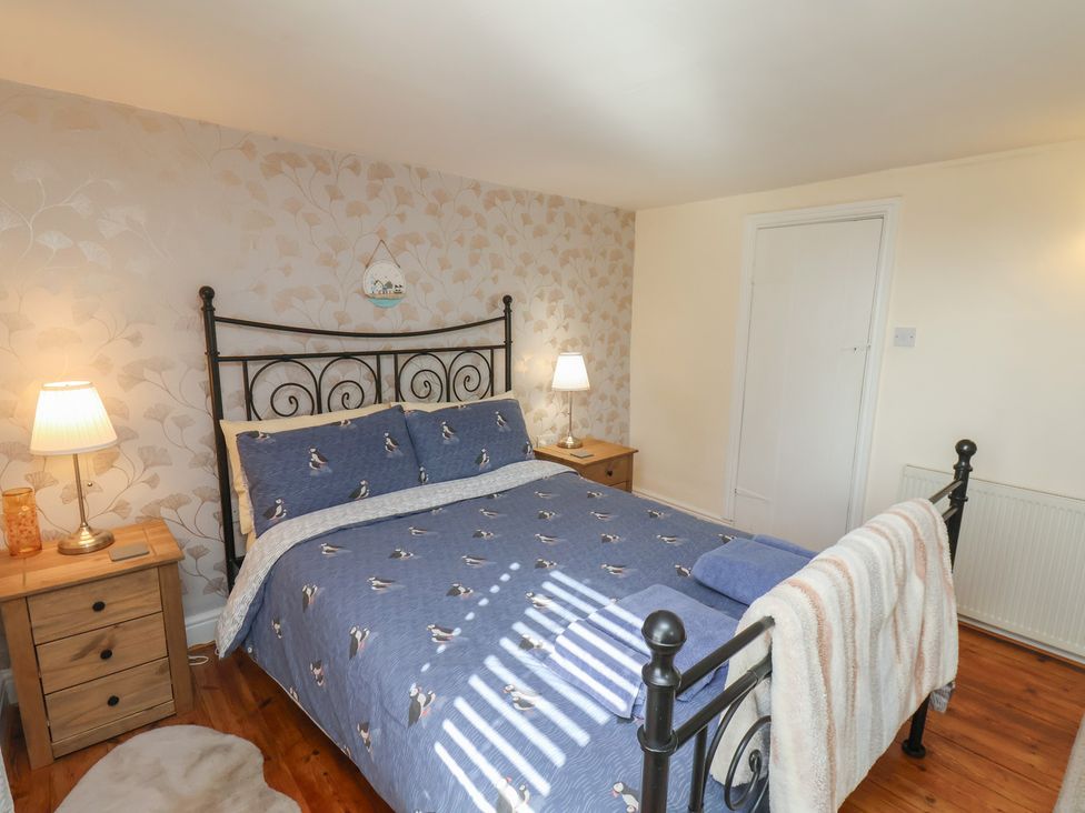 A bedroom with a bed and nightstand at Puffin's Nest