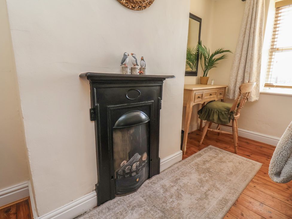A living room with a fireplace and table at Puffin's Nest