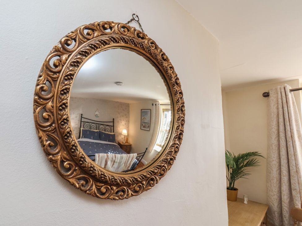 A bedroom with a mirror reflecting the bed and decor at Puffin's Nest