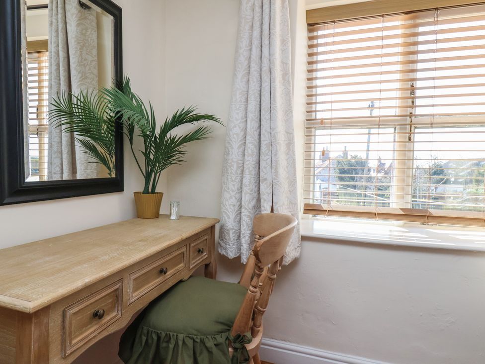 A desk with a chair and a mirror in a bedroom at Puffin's Nest 