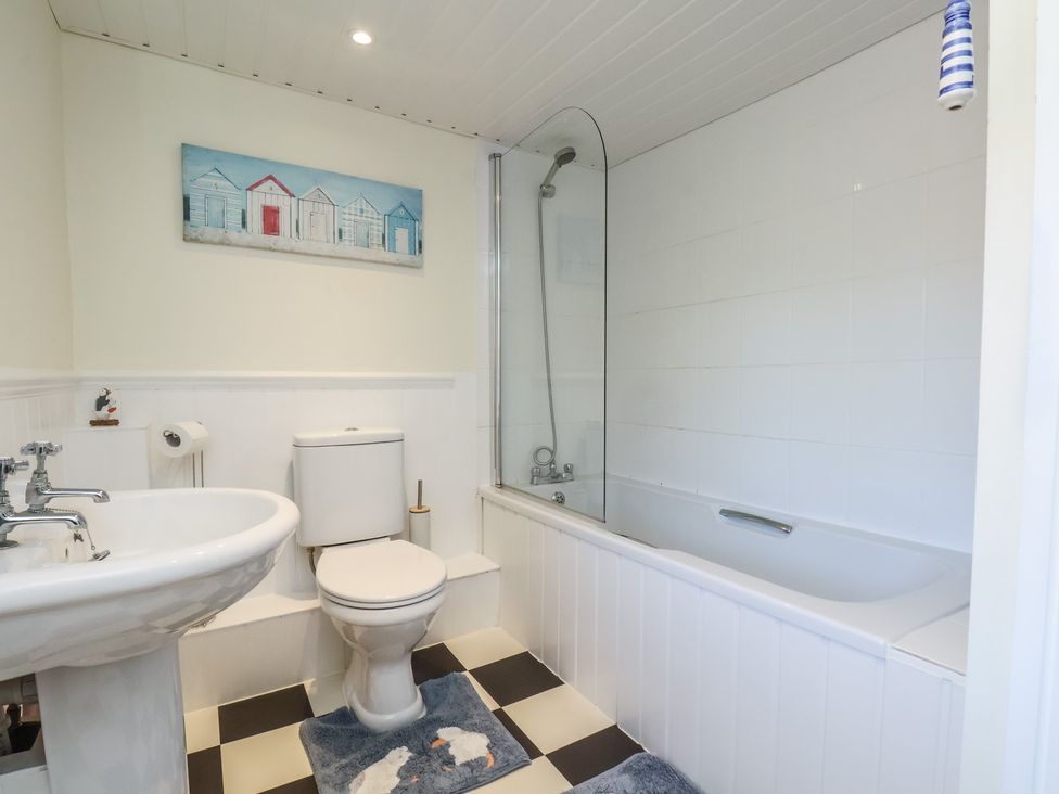 A bathroom with a bathtub, toilet, and sink at Puffin's Nest
