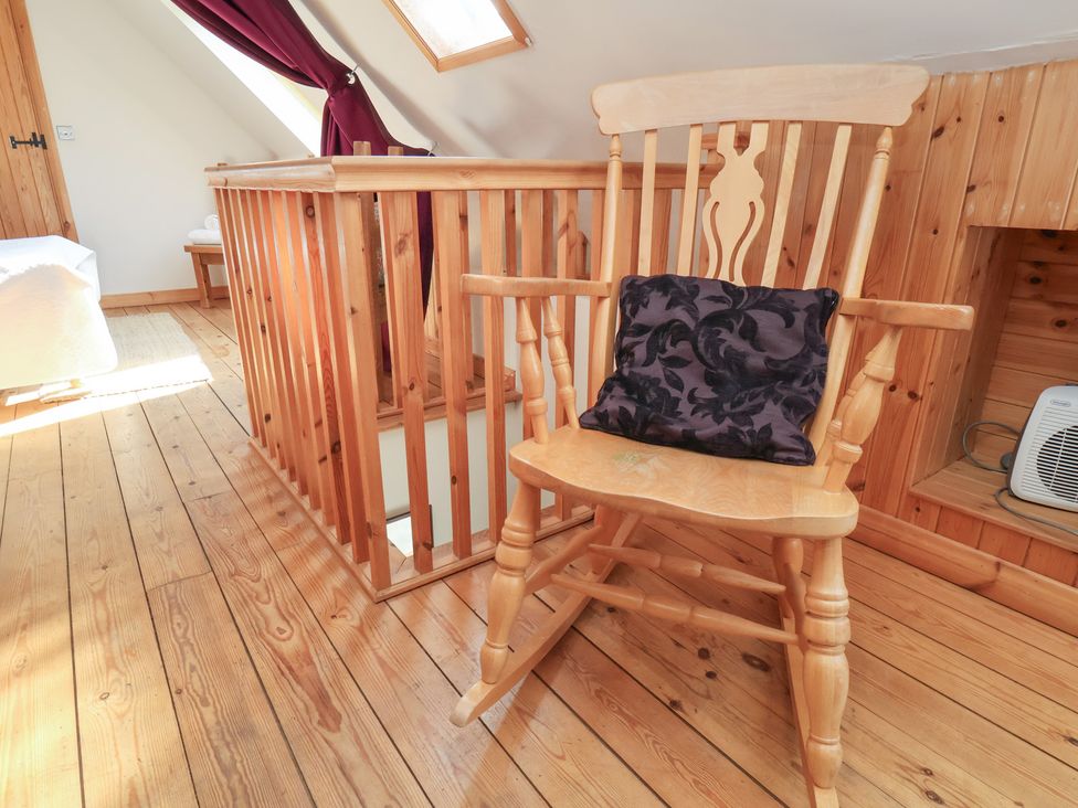 A loft area with a rocking chair and wooden railing at Horseshoe Cottage Ingleby Greenhow near Great Ayton