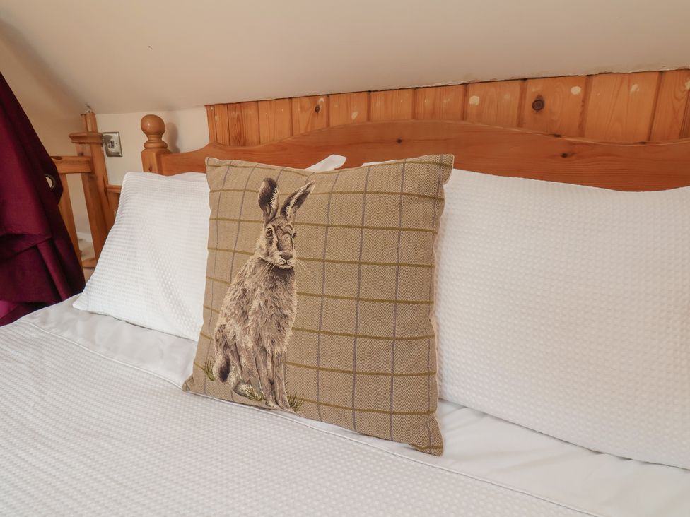 A bed with a pillow featuring a hare design at Horseshoe Cottage Ingleby Greenhow near Great Ayton