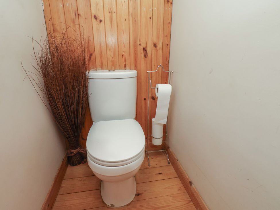 A bathroom with a toilet and toilet paper holder at Horseshoe Cottage Ingleby Greenhow near Great Ayton