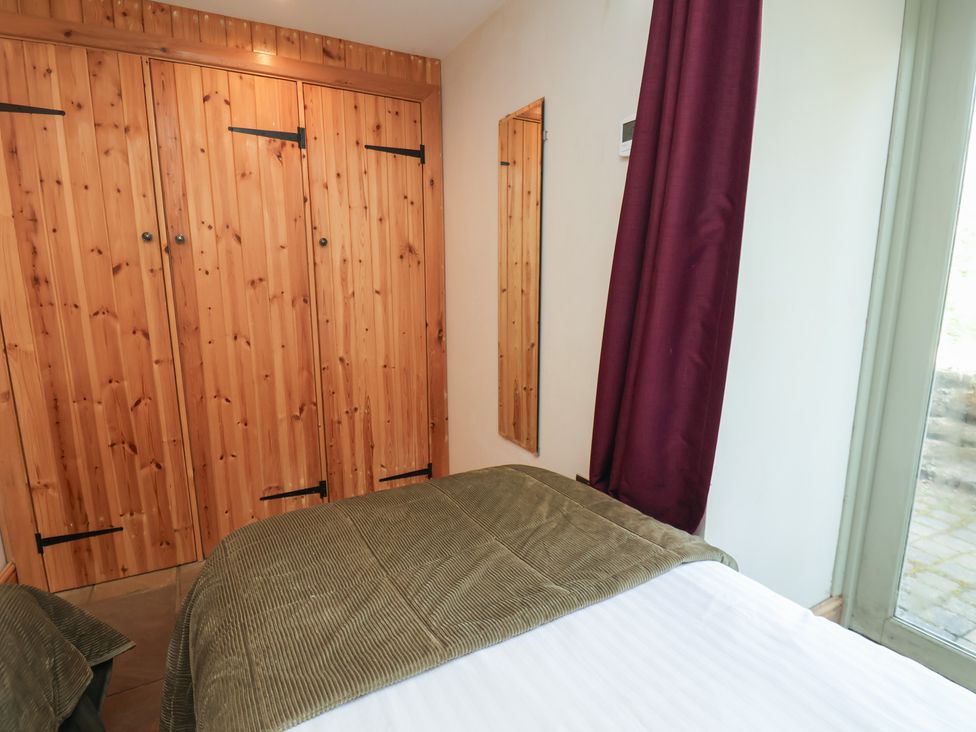 A bedroom with a wardrobe and a bed at Horseshoe Cottage Ingleby Greenhow near Great Ayton