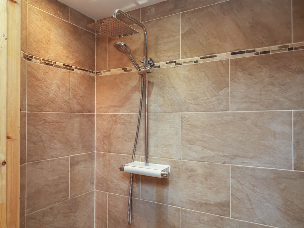 A shower with wall tiles and shower head at Horseshoe Cottage Ingleby Greenhow near Great Ayton