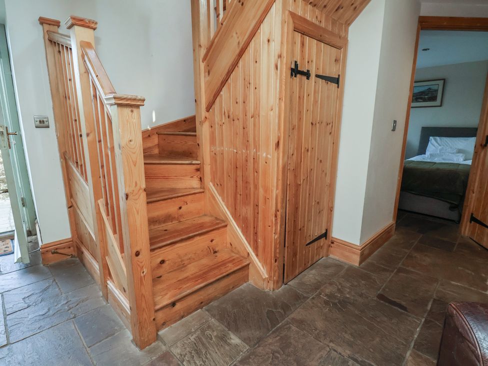 A staircase with wooden handrail and storage cabinet in the hallway at Horseshoe Cottage Ingleby Greenhow near Great Ayton