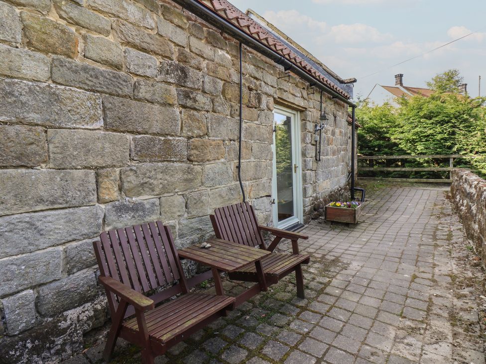 Outdoor seating area with wooden chairs and flower pot at Horseshoe Cottage Ingleby Greenhow near Great Ayton