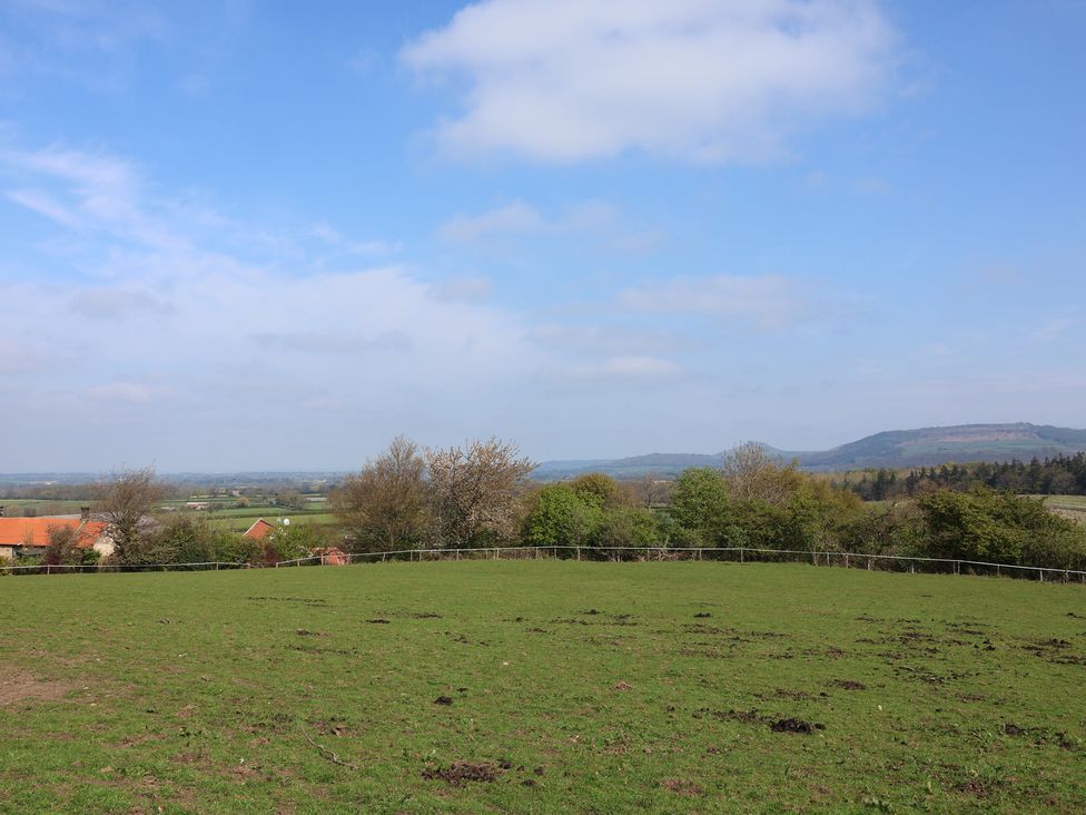 A field with trees and houses in the background at Horseshoe Cottage Ingleby Greenhow near Great Ayton