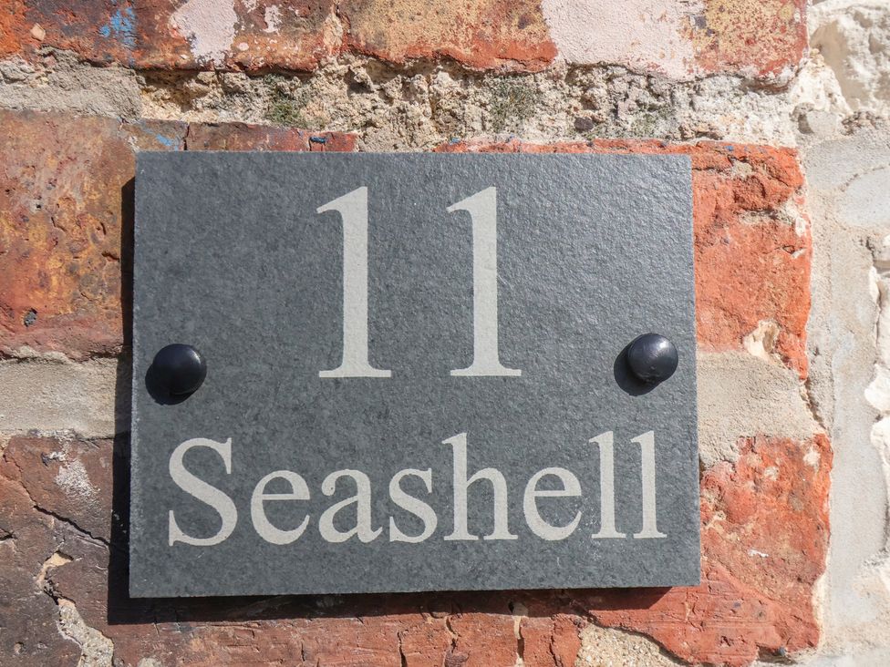 A house number plaque mounted on a brick wall at Seashell Cottage
