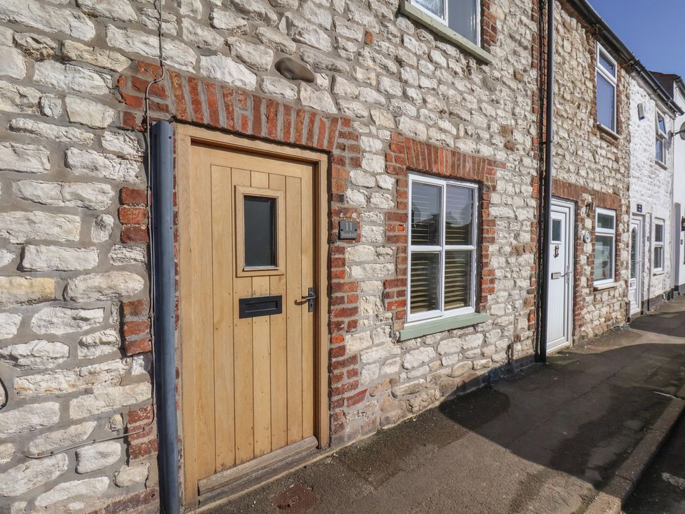 A stone wall with a wooden door and windows at Seashell Cottage