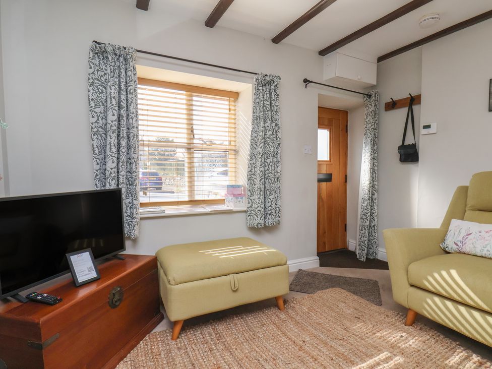 A living room with a television and ottoman at Seashell Cottage