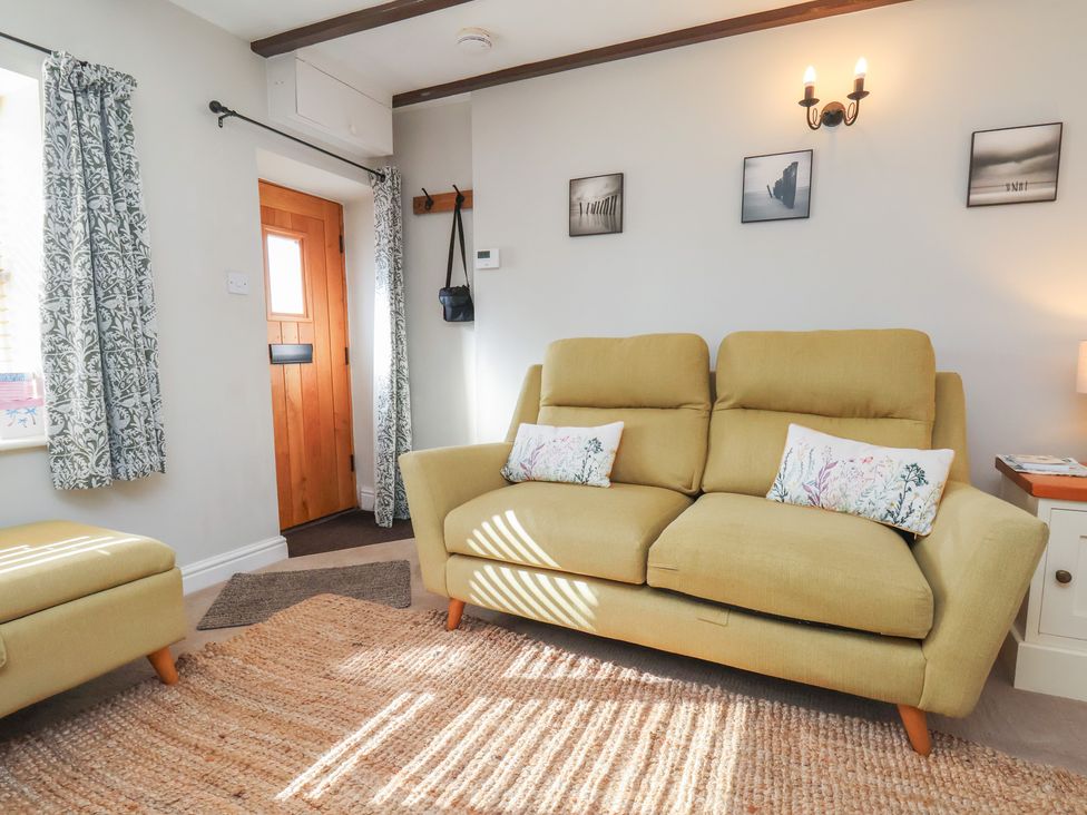 A living room with a sofa and armchair at Seashell Cottage
