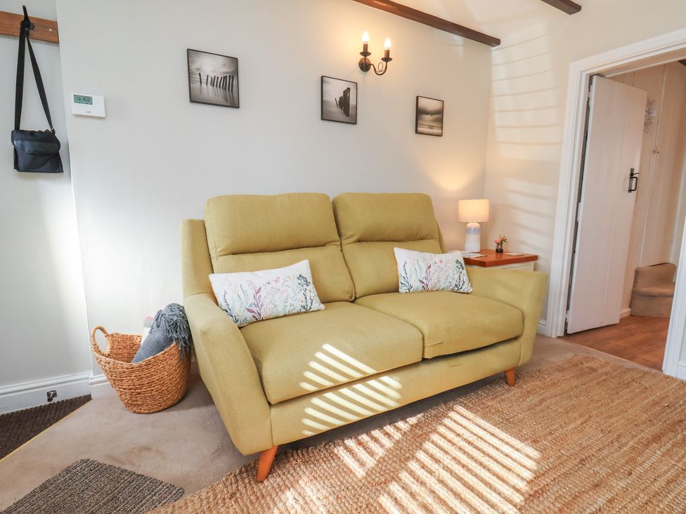 A living room with a sofa and side table at Seashell Cottage