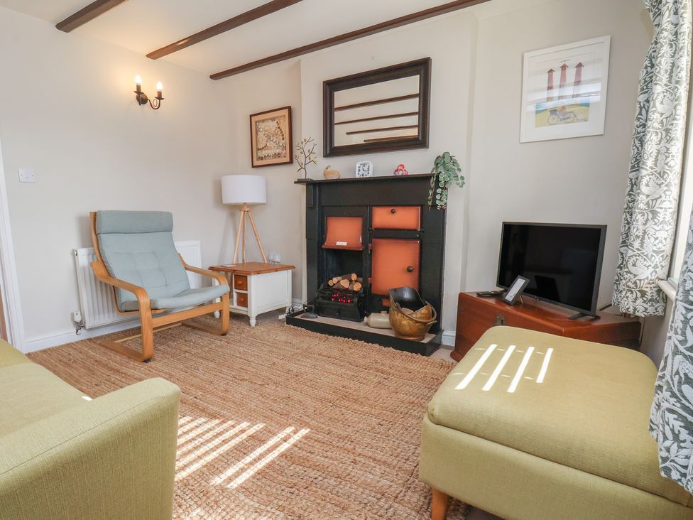 A living room with a fireplace and armchair at Seashell Cottage in 